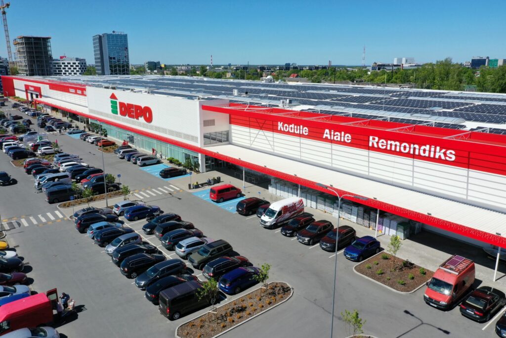 DEPO kaubanduskeskus ülaltvaates, esiplaanil lai punase-valge fassaad ja autosid täis parkla.
