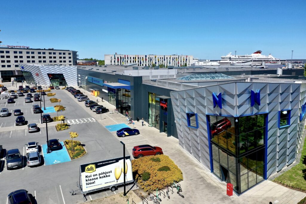 Nautica keskuse kaasaegne hoonekompleks päikesepaistelisel päeval, esiplaanil rekonstrueeritud fassaad ja sissepääsuala.