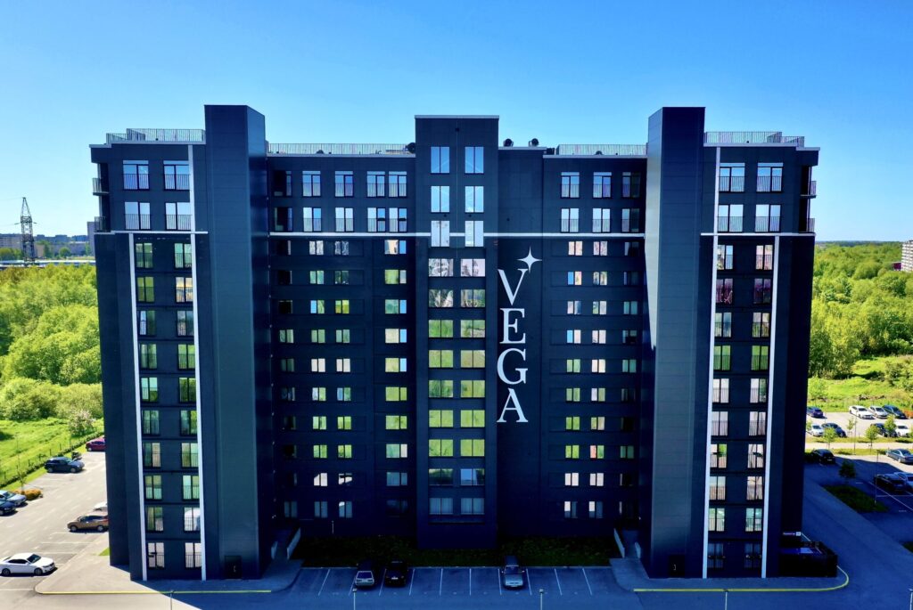 Mustakivi 25 kaasaegne kortermaja päikesepaistelisel päeval. Sirgjoonelise musta fassaadi ja suurte akendega hoone.